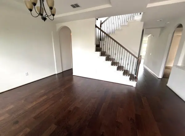 Finished two-story foyer with dark wood flooring, white walls, staircase with black metal railing, and hanging chandelier in Austin, TX.