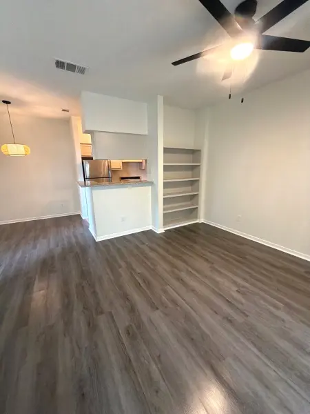 Finished open-concept living area with new vinyl plank flooring, freshly painted white drywall, open shelving, and ceiling fan in Austin, TX.