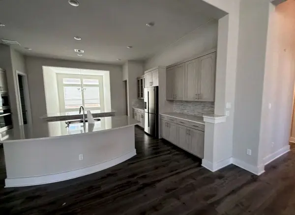 Newly renovated kitchen with white cabinetry, stainless steel appliances, dark wood flooring, gray paint, and recessed ceiling lights in Briarcliff, TX.