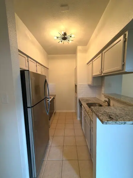 Clean, well-lit kitchen with new ceiling-mounted starburst light fixture, granite countertops, stainless steel appliances, and white subway tile backsplash in Austin, TX.